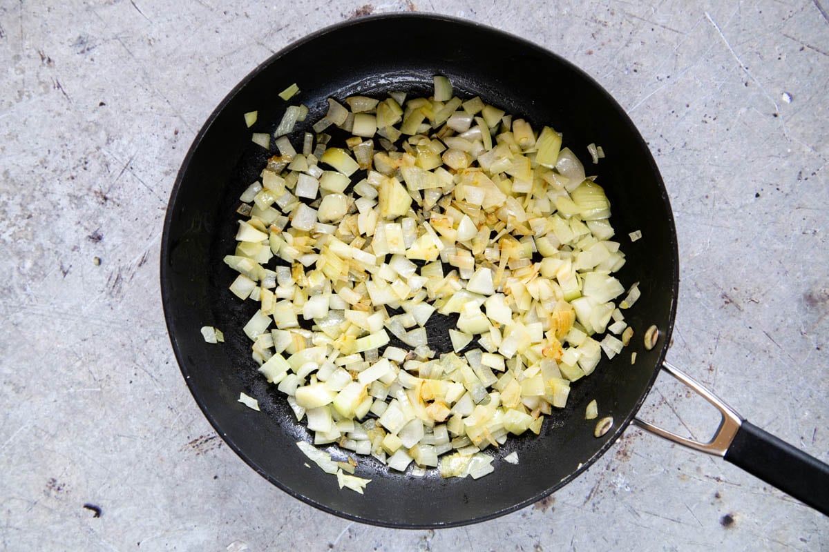Onions frying in a large frying pan.