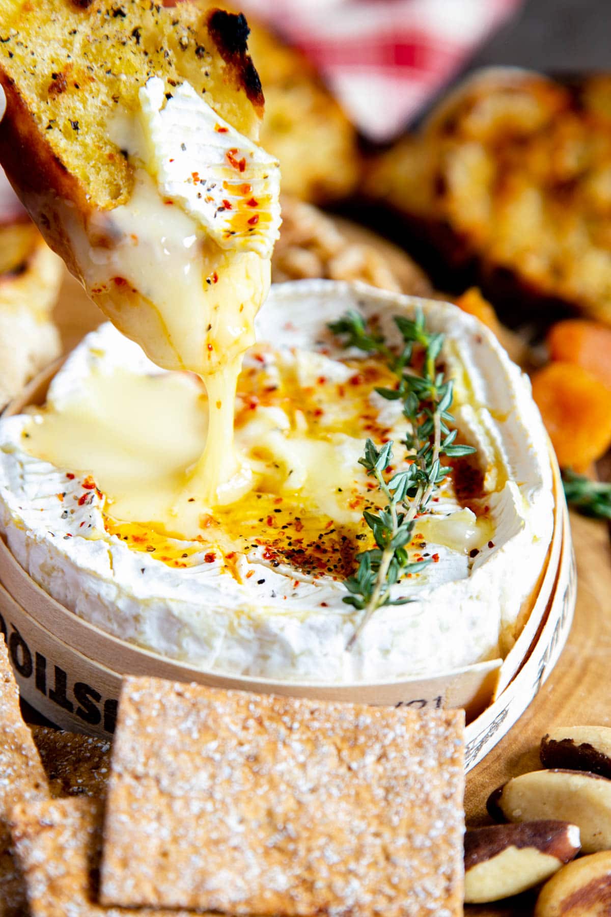 Gooey delicious camembert drips from a toasted slice of baguette. The tasty runny cheese is garnished with a sprig of thyme.