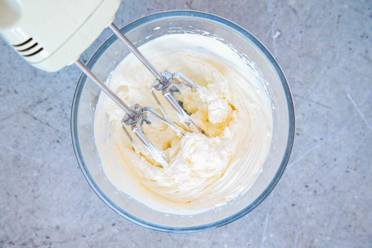 A glass bowl of heavy or double cream whipped to soft peaks using electric beater.