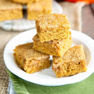 A close up of a stack three hight of yummy pumpkin spice blondies, on a side plate.