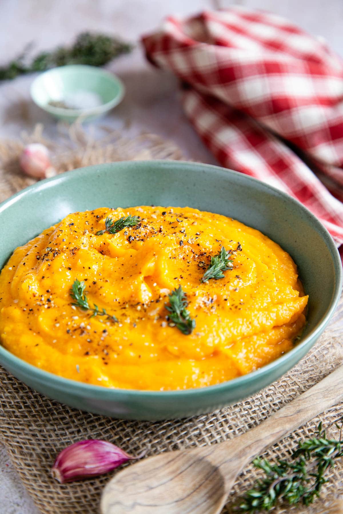 Golden butternut squash mash in a green bowl, laid out on the table to serve.