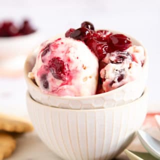 Juicy red cranberries combined with smooth vanilla ice cream, served in a dainty bowl with cookies on the side.