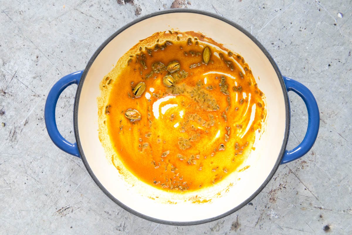 The turmeric, cardamom pods and cumin are shown cooking in a little oil.