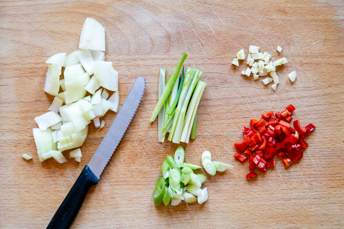 The vegetables chopped and ready to cook: diced onion, finely chopped garlic and finely chopped chilli. The spring onions are cut two ways, horizontally and vertically.