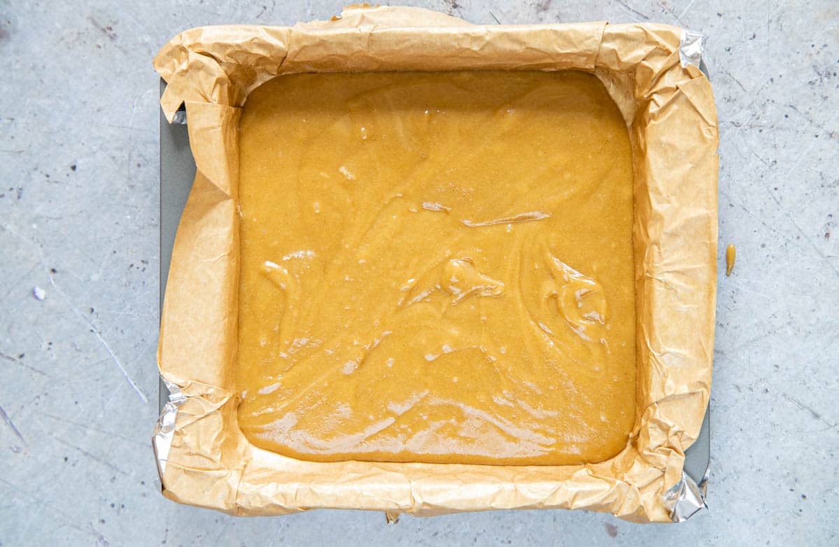 Pour the batter into the baking tray and smooth out to fill the edges.