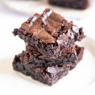A stack of three brownies with a crisp, papery crust and the deepest, darkest gooey centre.