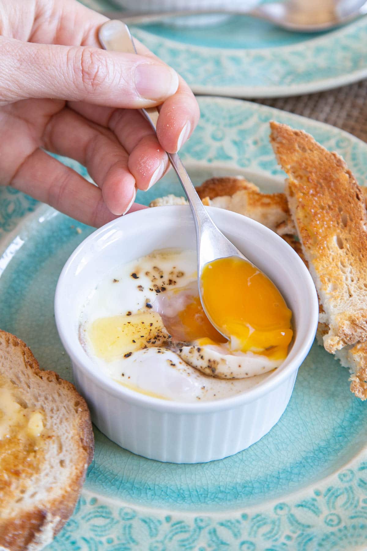 Breaking into the soft golden yoke with an egg spoon. These coddled eggs are delicious served with buttered toast.