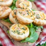 Close up of mini quiches Lorraine, the tops dotted with chopped chives.
