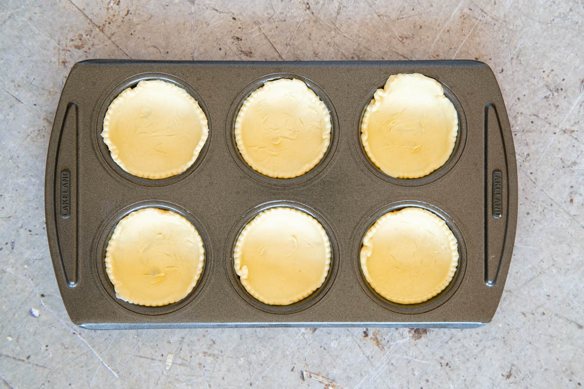 Arranging the pastry circles in the bun or muffin pan.
