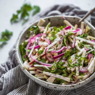 Striking purple strings of pickled red onion top this dish of apple and celeriac coleslaw, with a contrasting sprinkle of green coriander leaf.