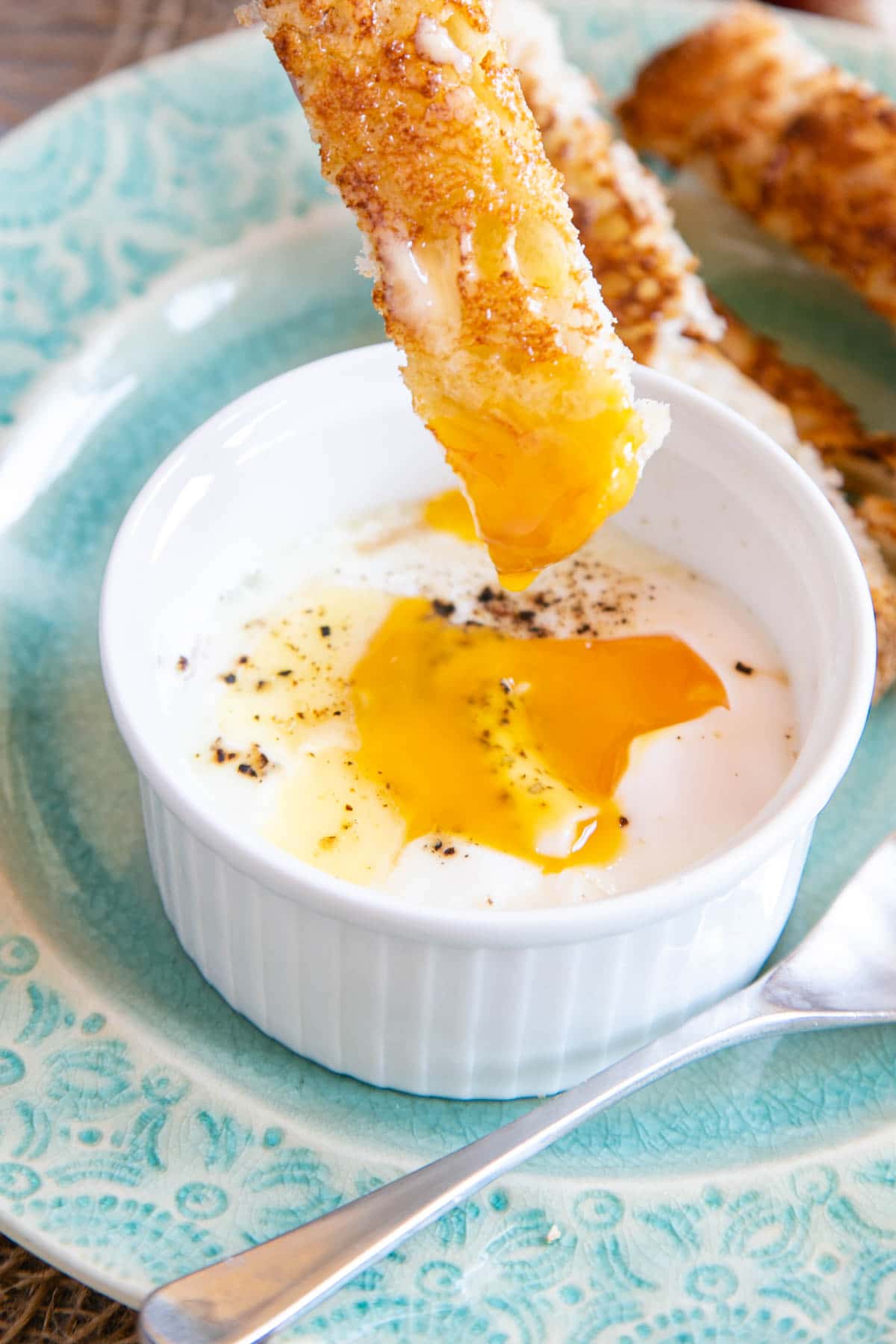 Dipping in to the golden yolk of a coddled egg in a ramekin dish