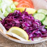 Vibrant red cabbage contrasts with the fresh green of lettuce and cucumber, red tomatoes and yellow lemon wedges, making a feast for the eyes too.