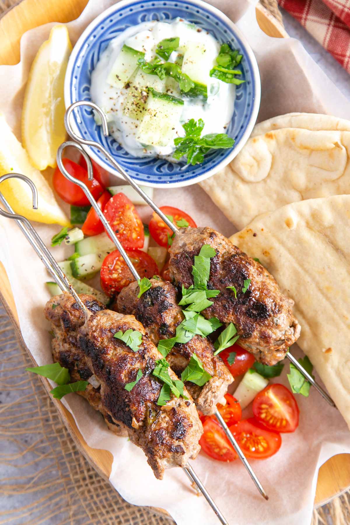 View from above of the lamb kofta skewers ready to serve with tzatziki, salad and bread.