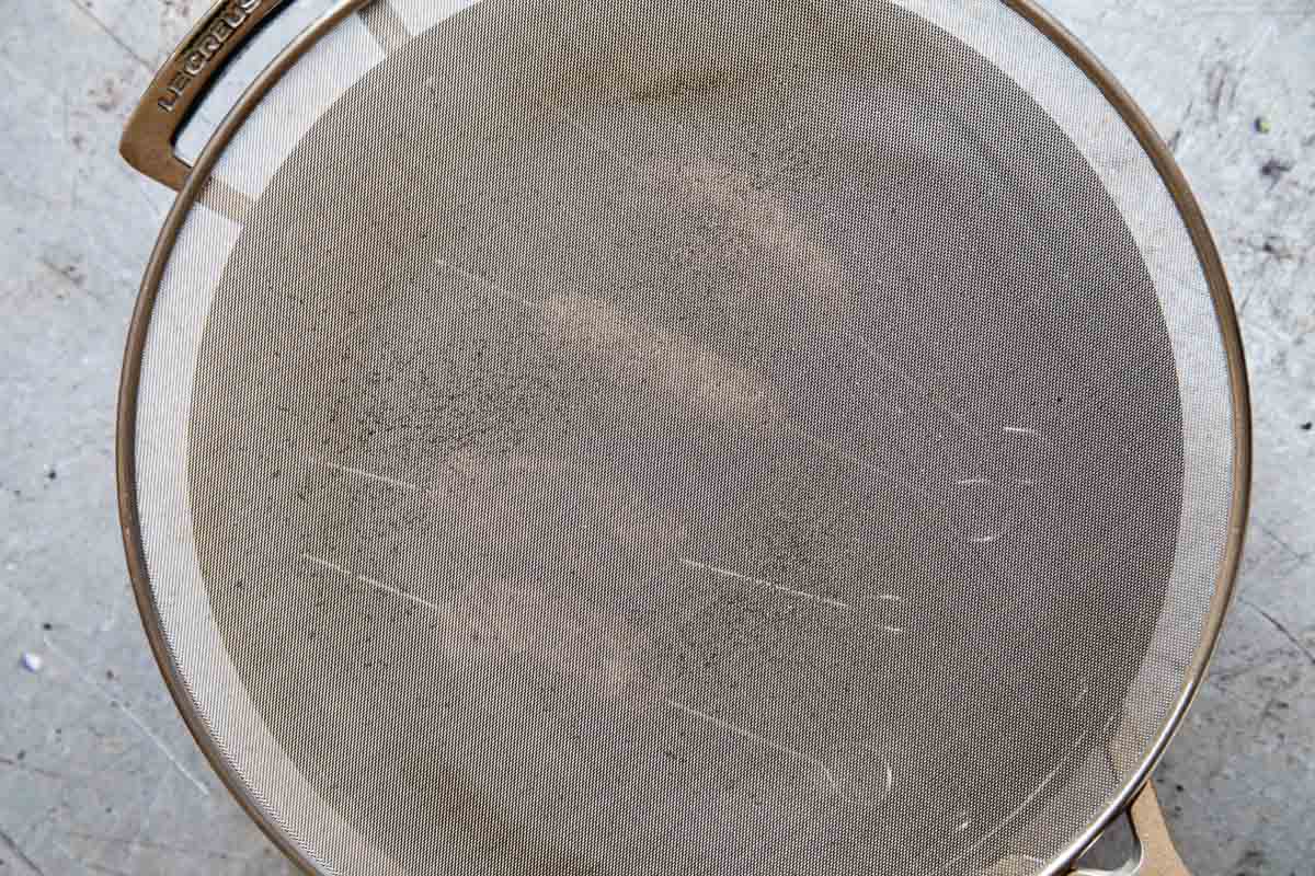 A mesh cover placed over the pan helps to prevent mess and burns.