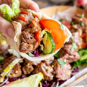 Turkish style lamb shish kebabs: chunks of tender meat with a drizzle of spicy sauce, served with flatbread and a colourful salad.