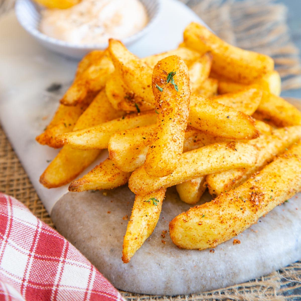 Delicious spicy peri peri fries, served on a marble board with homemade spicy peri peri mayo.