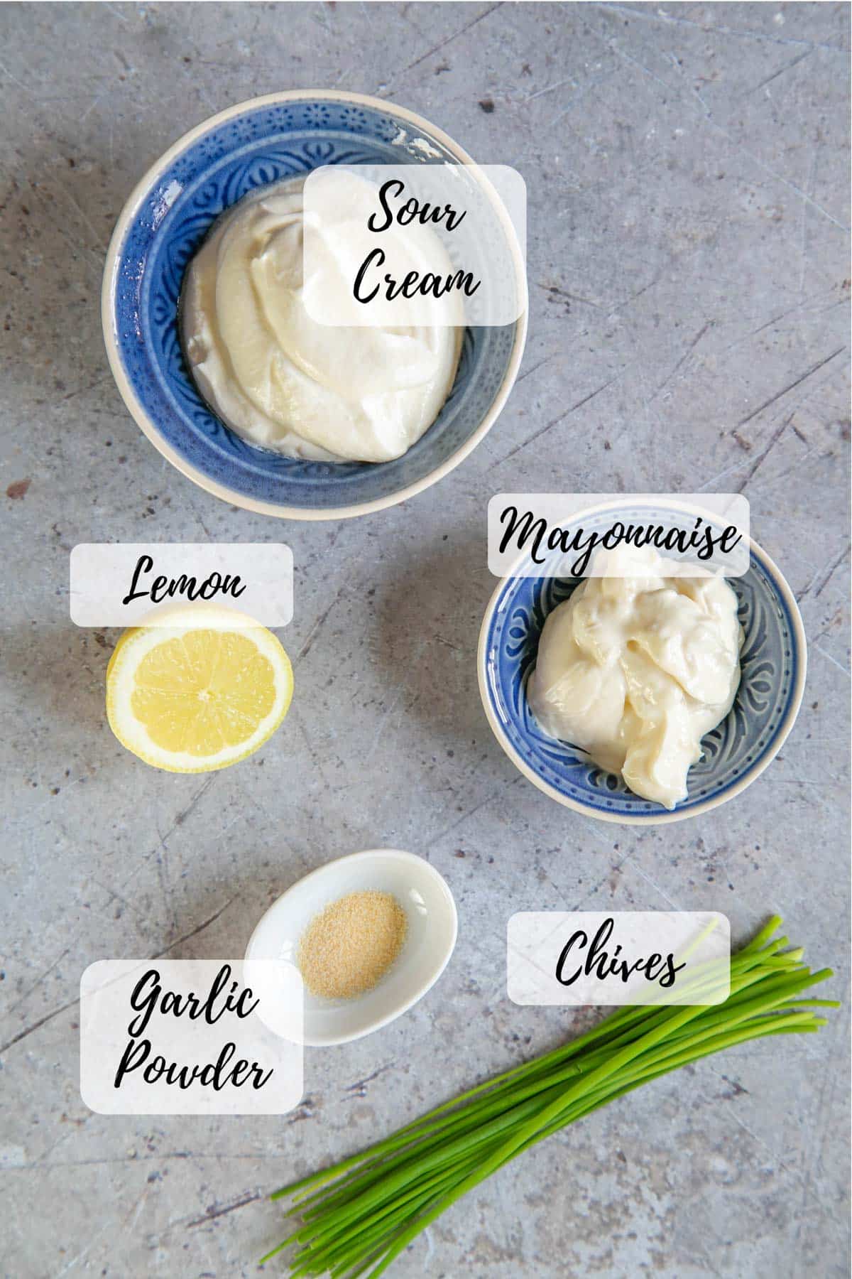 Ingredients for sour cream and chives dip, gathered and ready to prepare: sour cream, mayonnaise, fresh chives, garlic powder and lemon juice.
