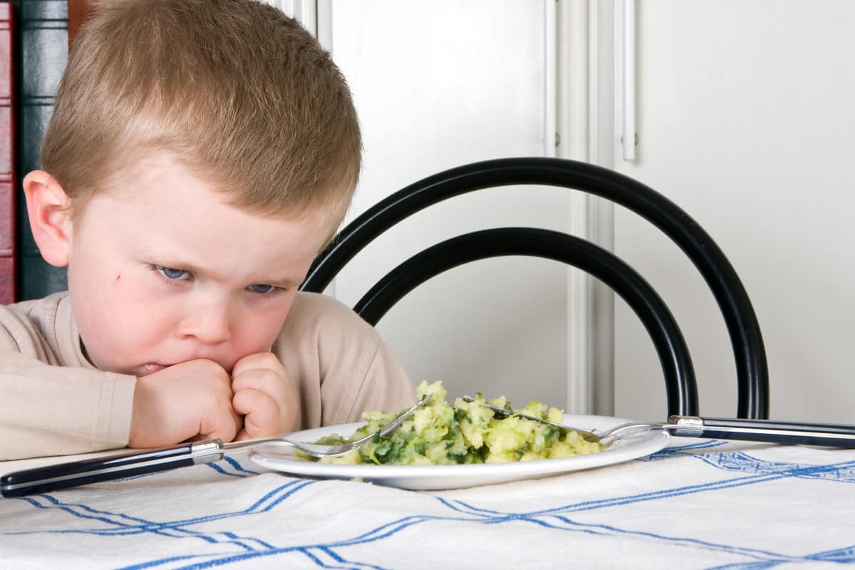 A small boy refusing to eat a plate of salad - not everyone likes salad cream!