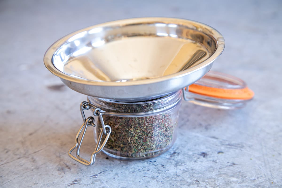 Using a funnel to transfer the seasoning mix to a storage jar avoids spills and waste.