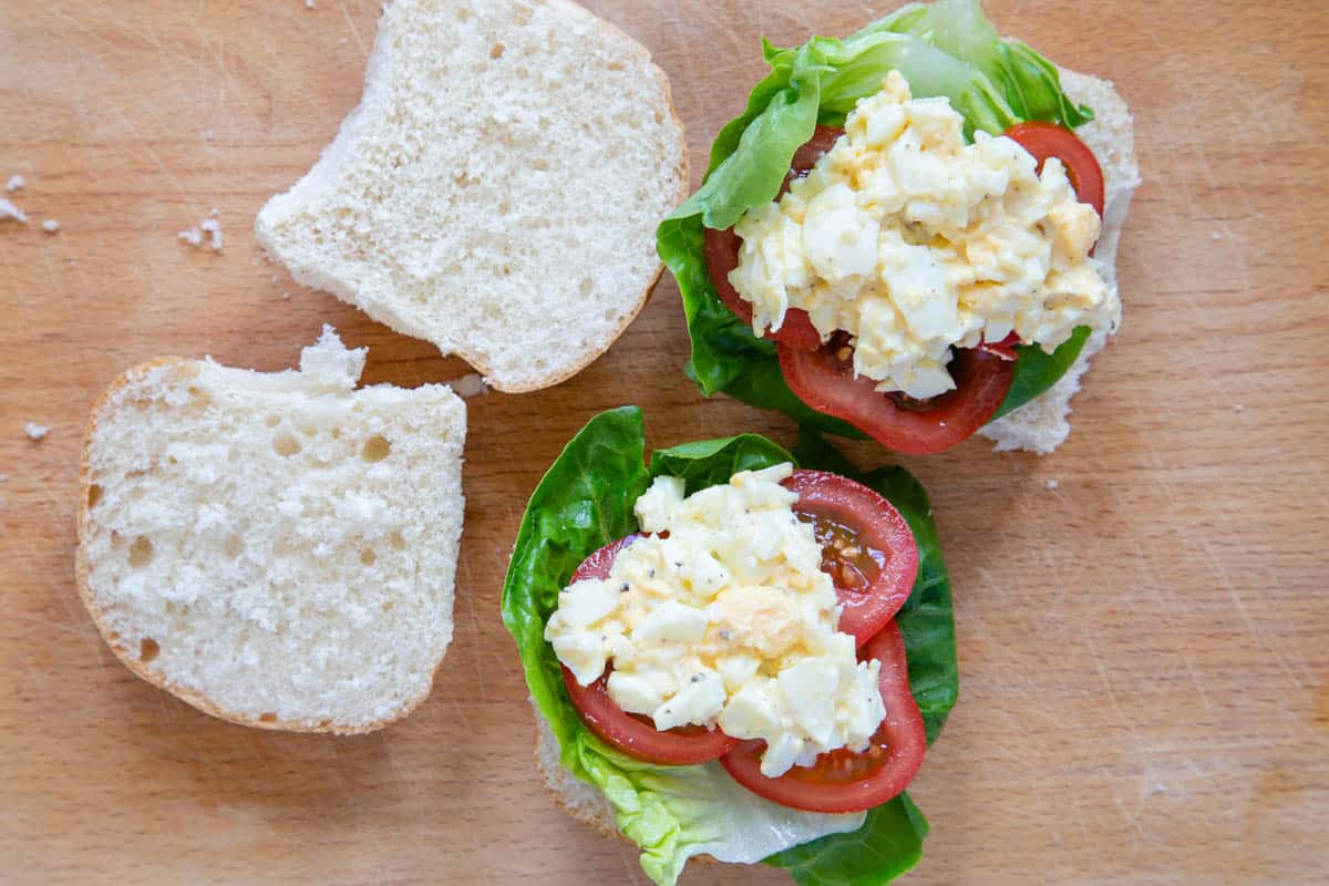 The lettuce, tomato and egg-salad cream mix layered up on a white roll.
