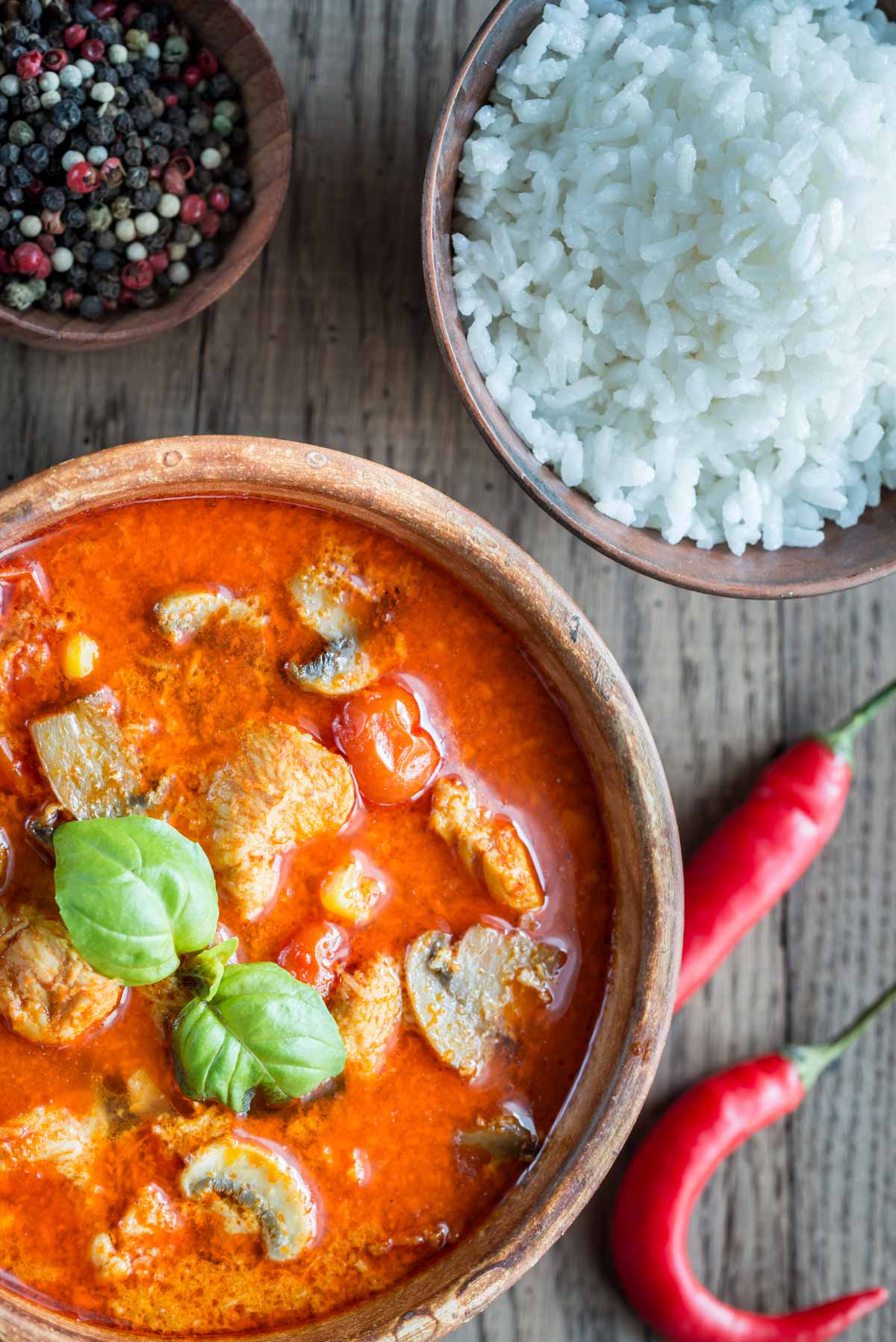 Rich red curry, vibrant in colour, garnished with basil and served with rice
