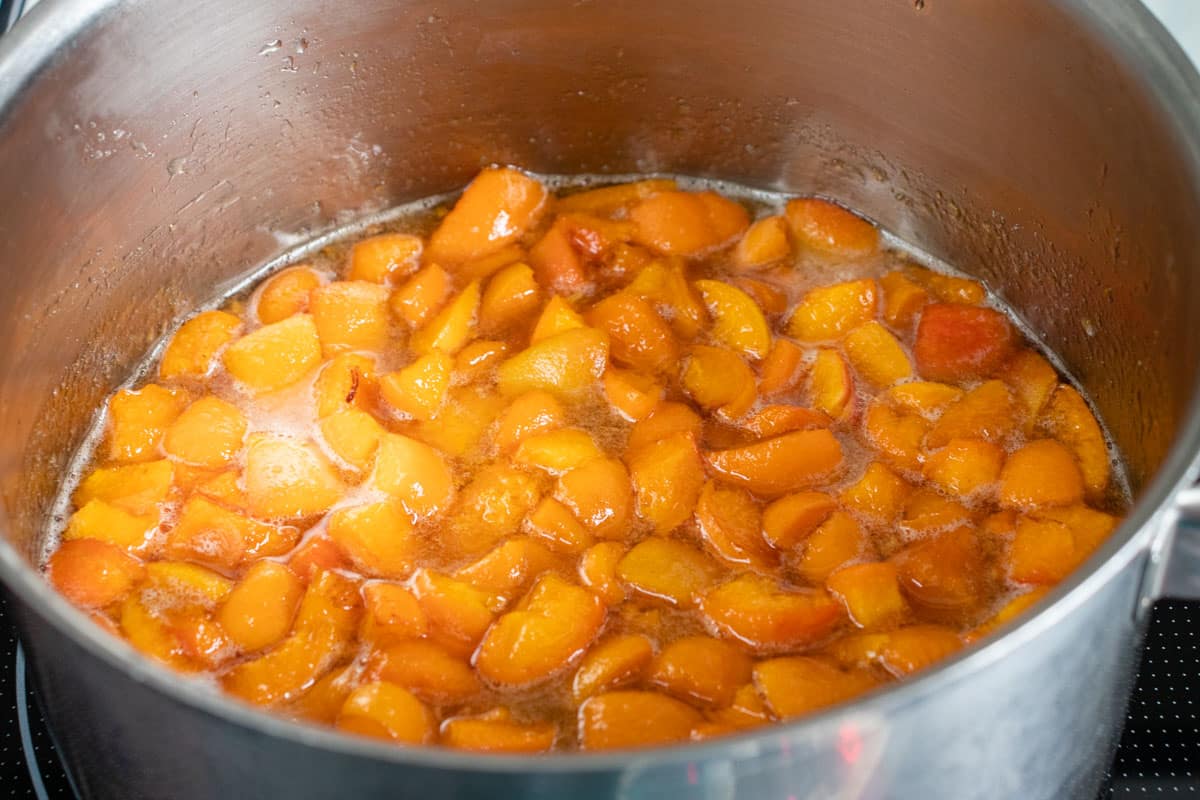 The ingredients for apricot jam in a pan, cooking gently to melt the sugar. It is important to have plenty of space above the level of the fruit in the pan.