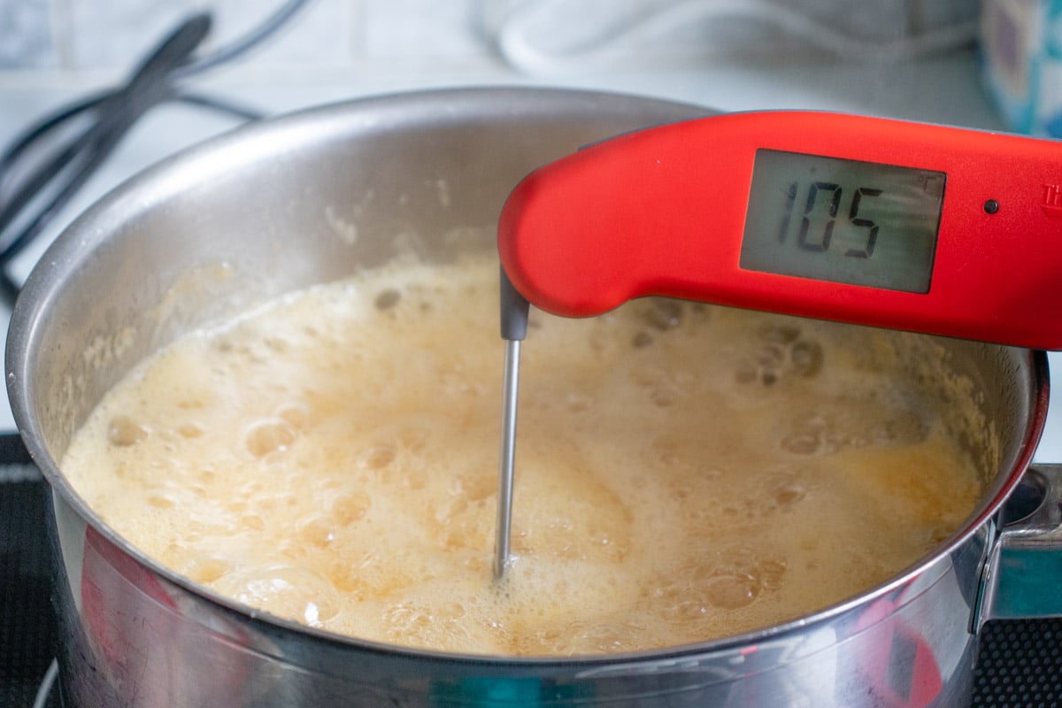 Testing the temperature of the bubbling jam with a digital kitchen thermometer.