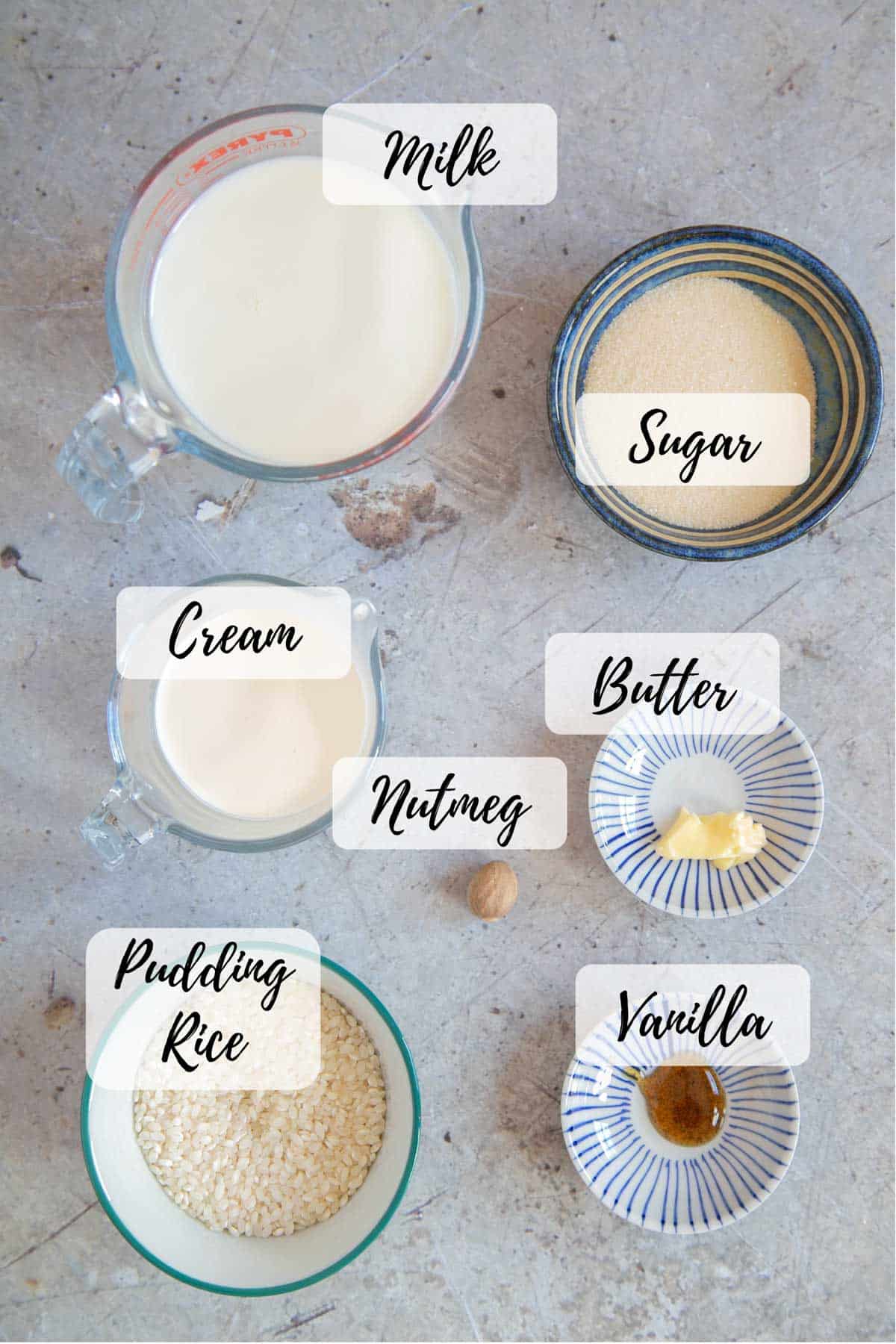 The ingredients for baked rice pudding - pudding, rice, milk, cream, sugar, butter, vanilla and nutmeg,
