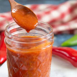 Hot thick red chili Relleno sauce fills a jam jar.