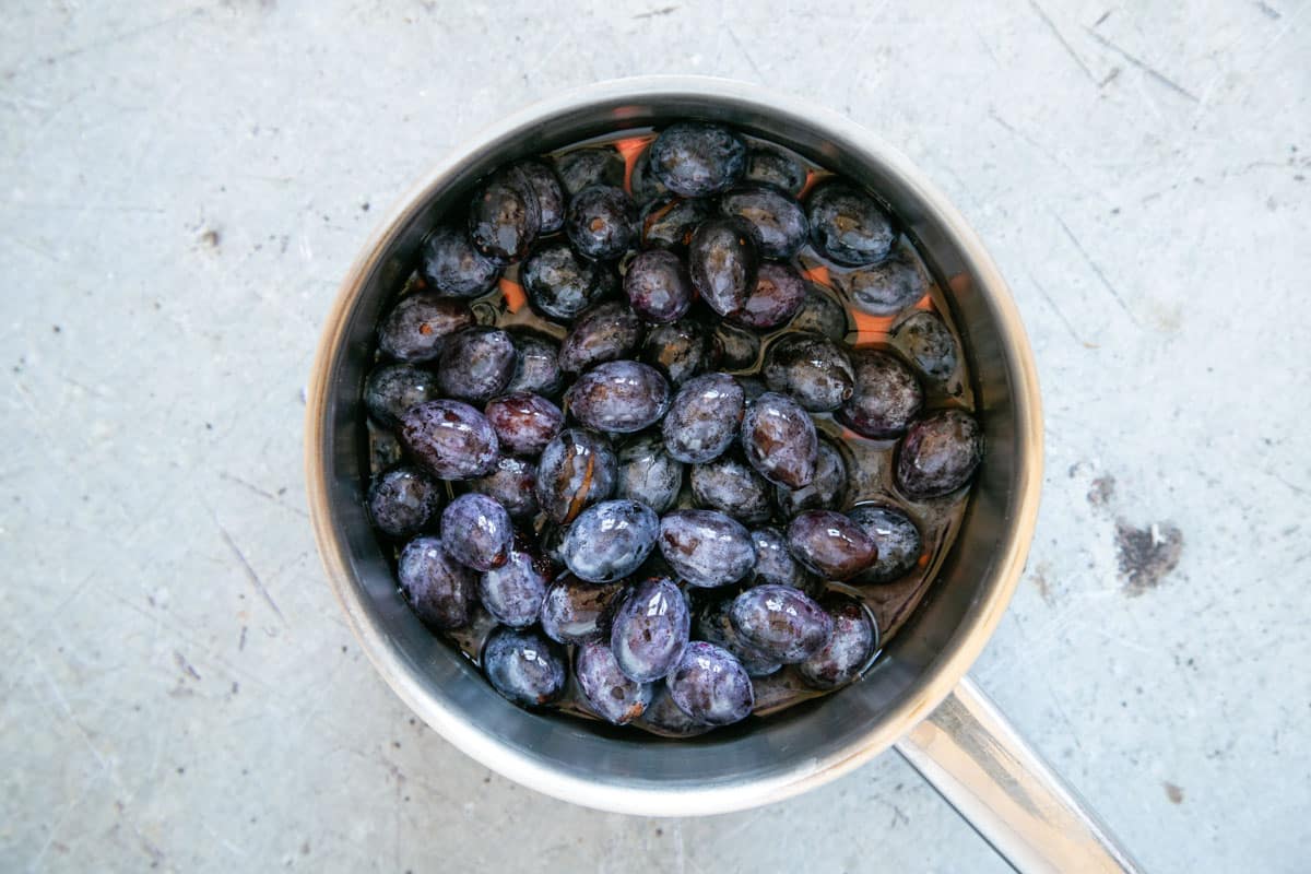 A saucepan full of damsons being cooked in a little water.
