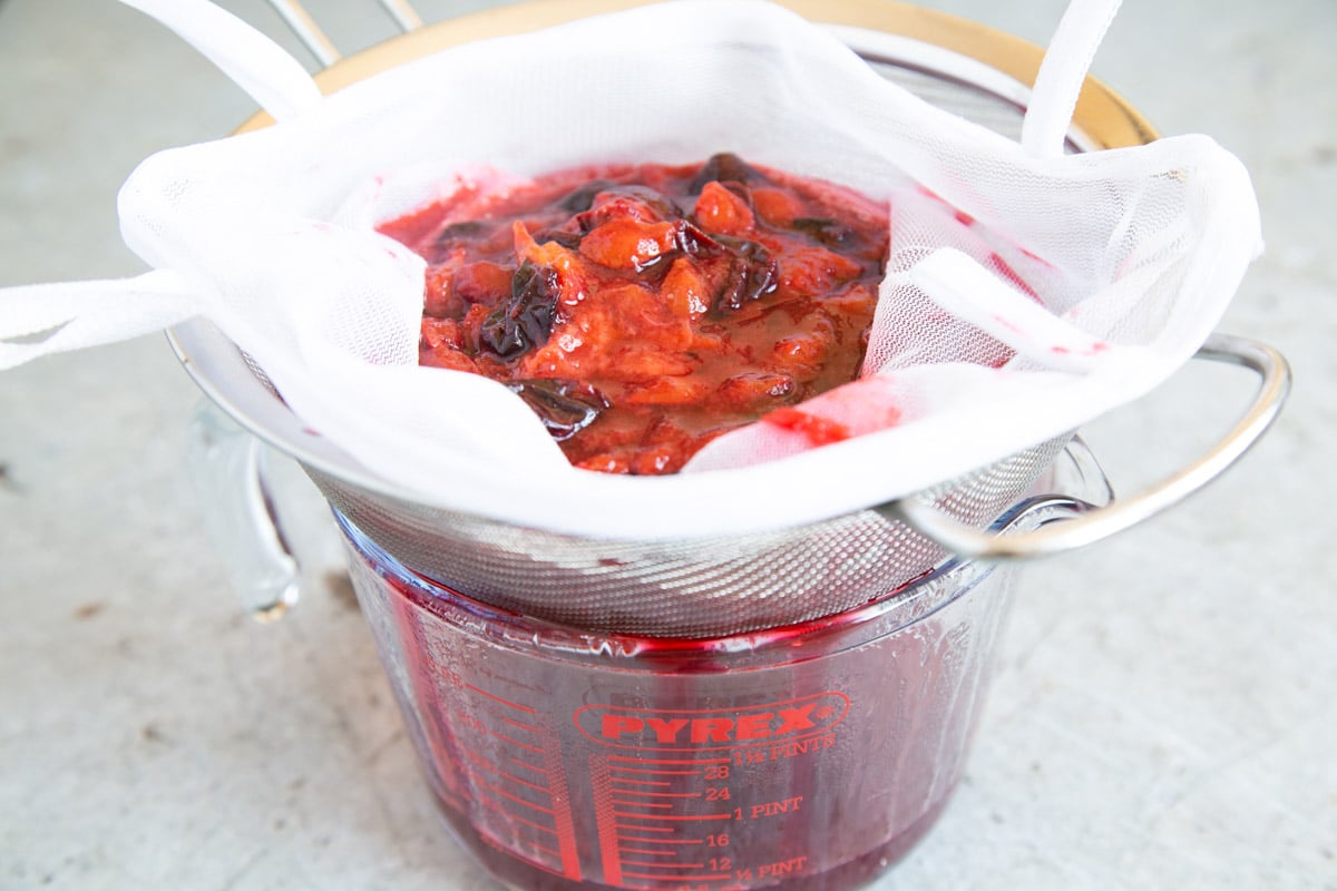 Cooked damsons are then ladled into a jelly bag over a sieve. This stops any splashing.