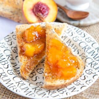 a close up of toast thickly spread with golden orange peach jam