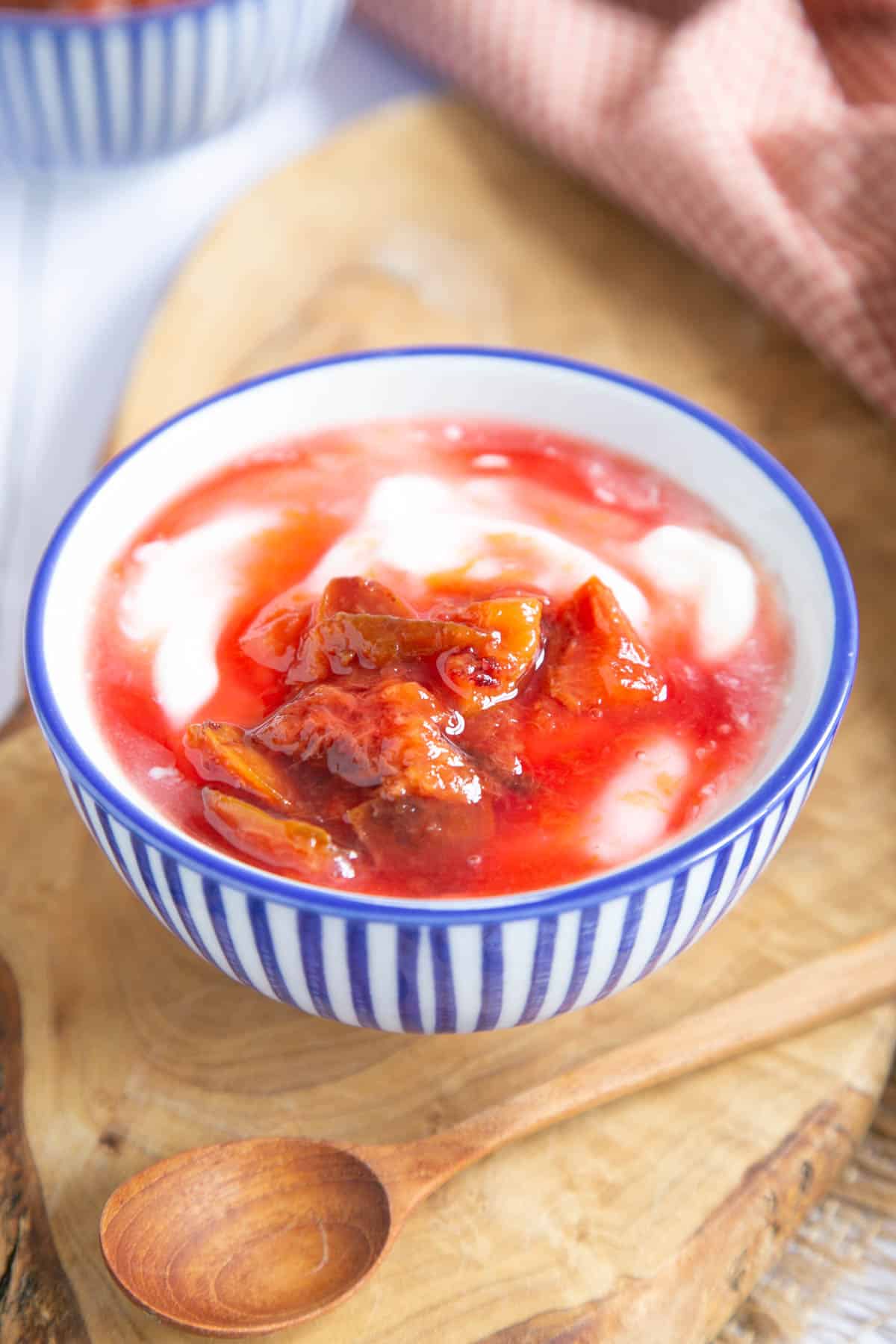 Delicious plum compote served as a topping to yoghurt; a wooden teaspoon in the foreground.