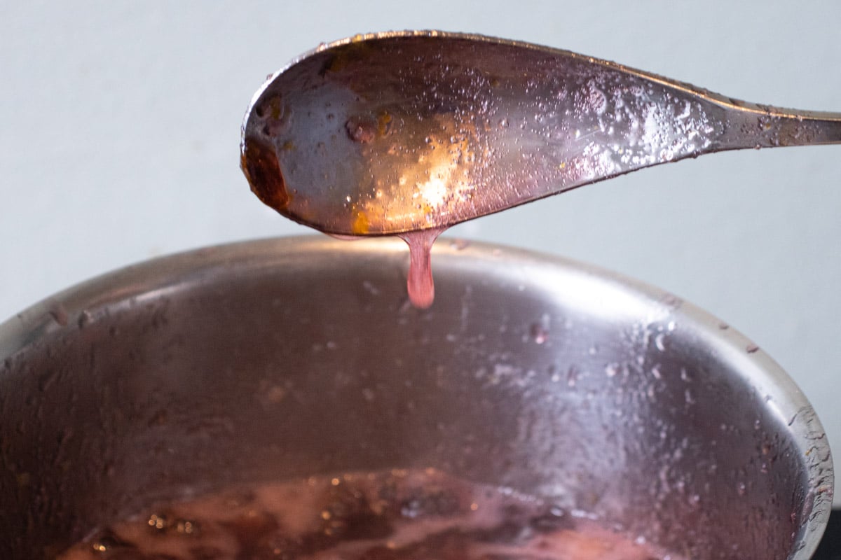 The flake test - a drop falls slowly from a metal spoon, leaving behind a flake of jam.