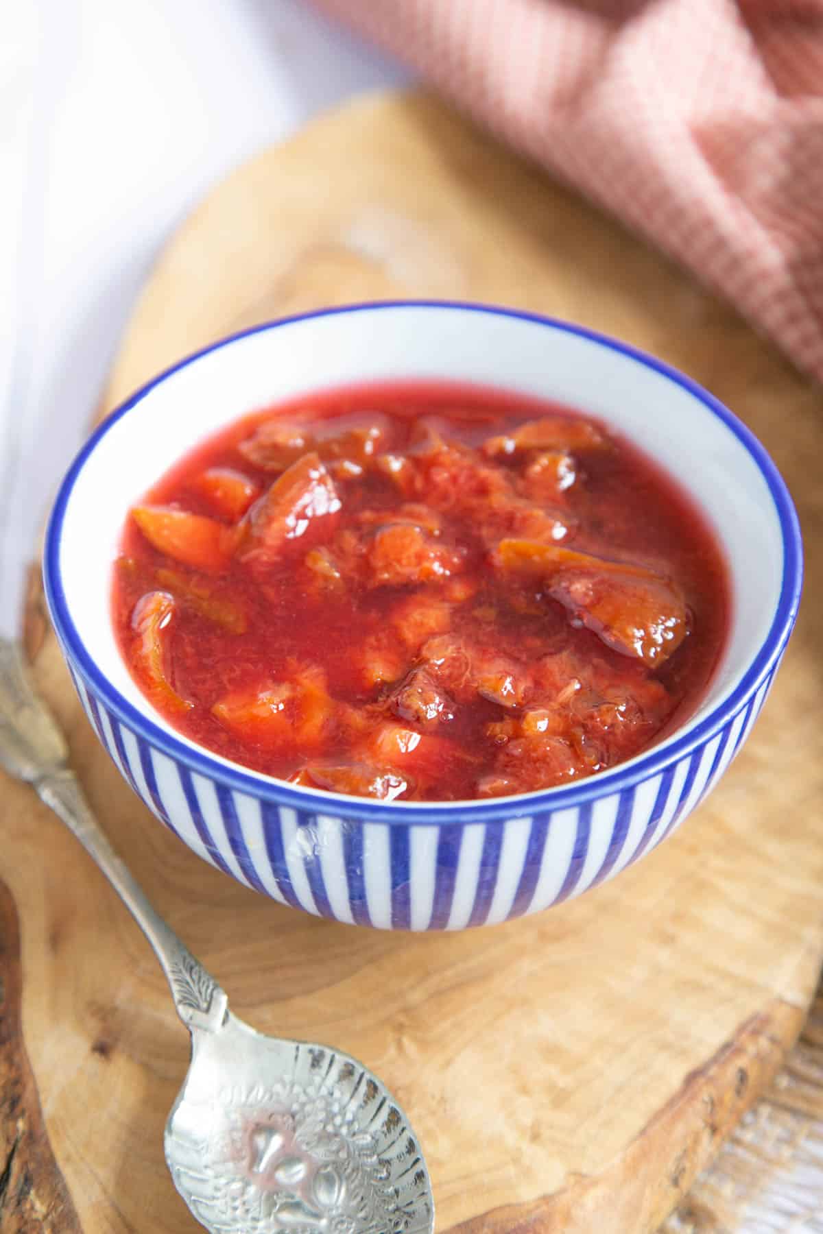 A bowl full of plum compote; the cooked plums are swimming in lots of delicious juice.