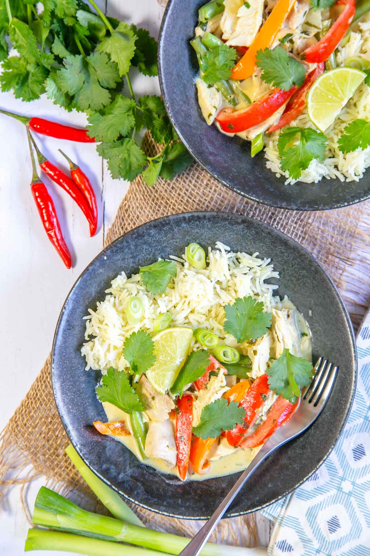 A table set with bowls of bright, colourful Thai chicken green curry and rice.