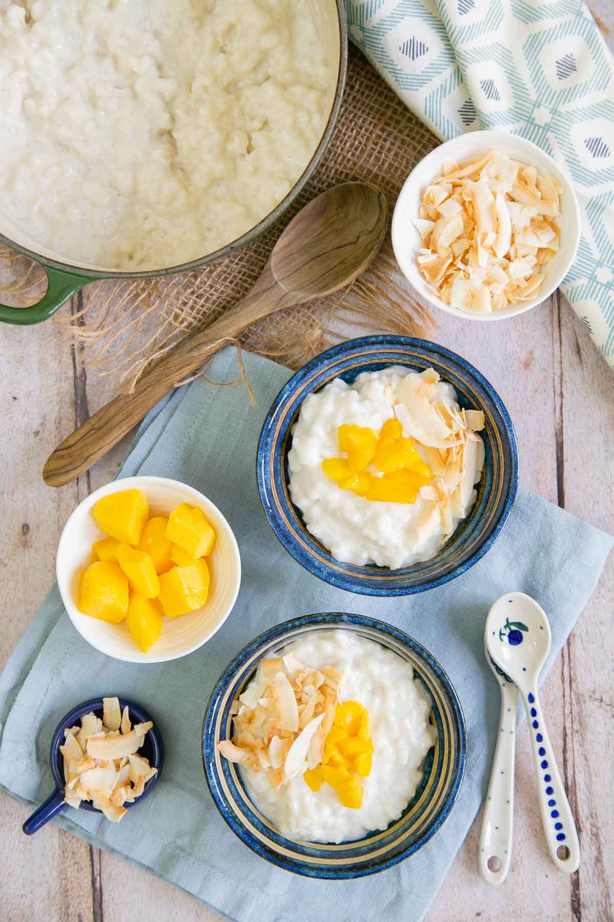 Coconut rice pudding topped with fresh mango and toasted coconut in pretty blue bowls.