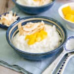 a bowl of rich coconut rice pudding topped with mango and coconut