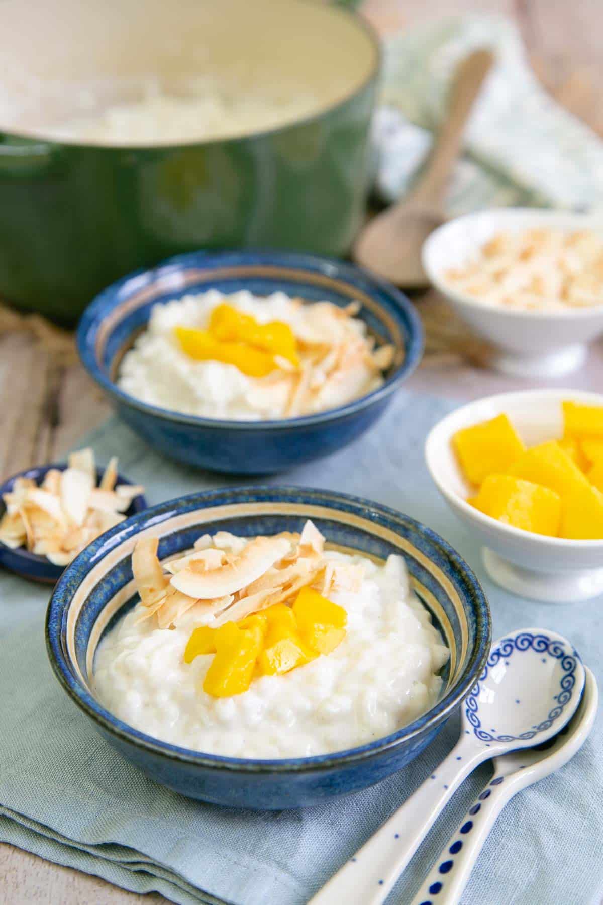 Luxurious bowls of coconut rice pudding topped with fresh mango and toasted coconut shavings.