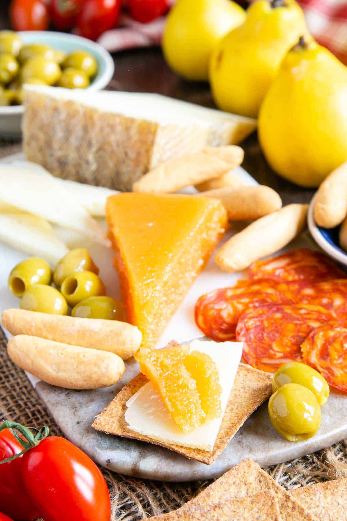 A golden wedge of membrillo or quince cheese served on a platter with cheese, olives and charcuterie.