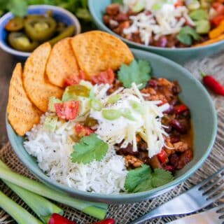 A warming bowl of rich ground turkey chili with rice, nacho chips and all the trimmings.