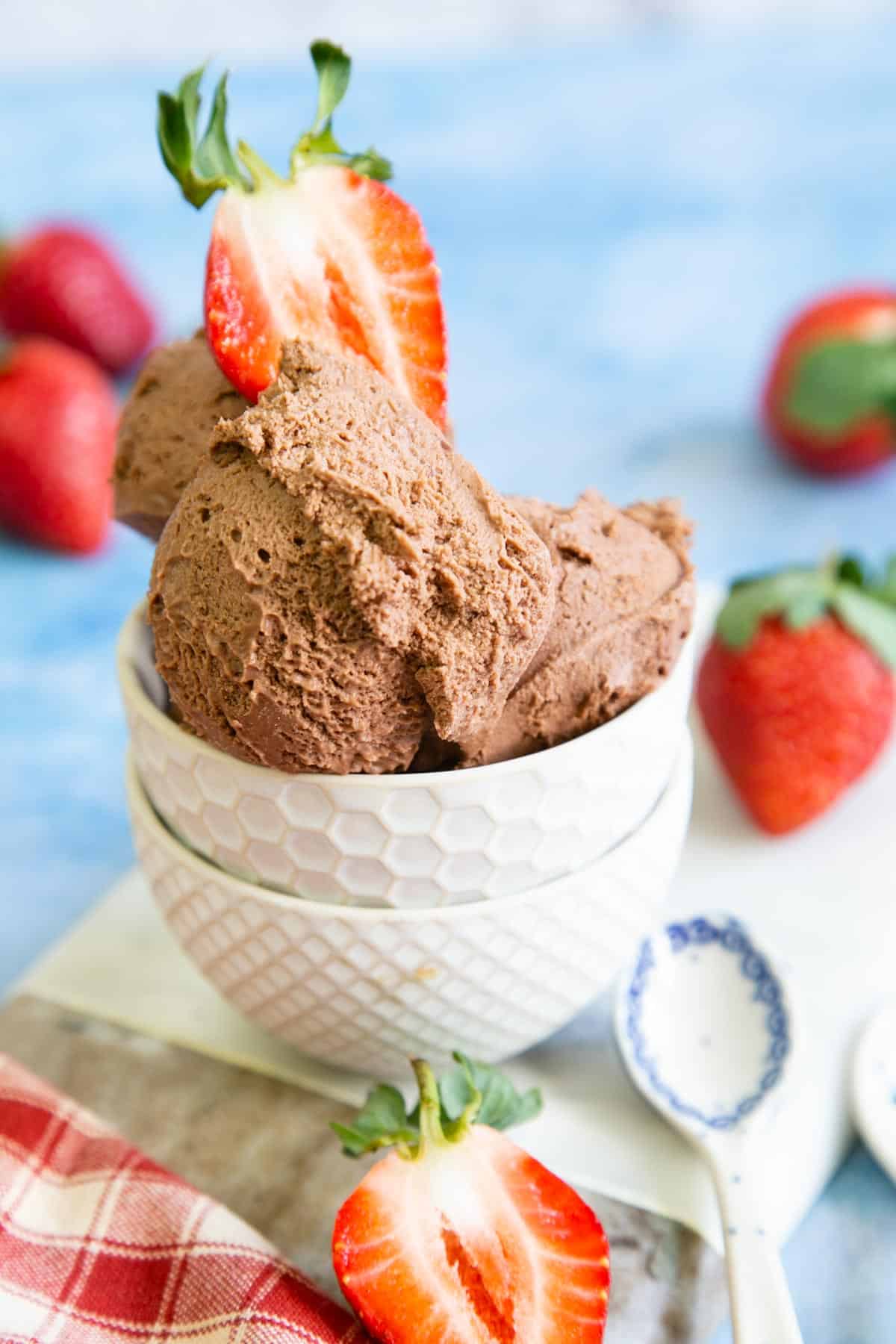 No-churn easy nutella ice cream in a pretty white bowl with strawberries on the side.