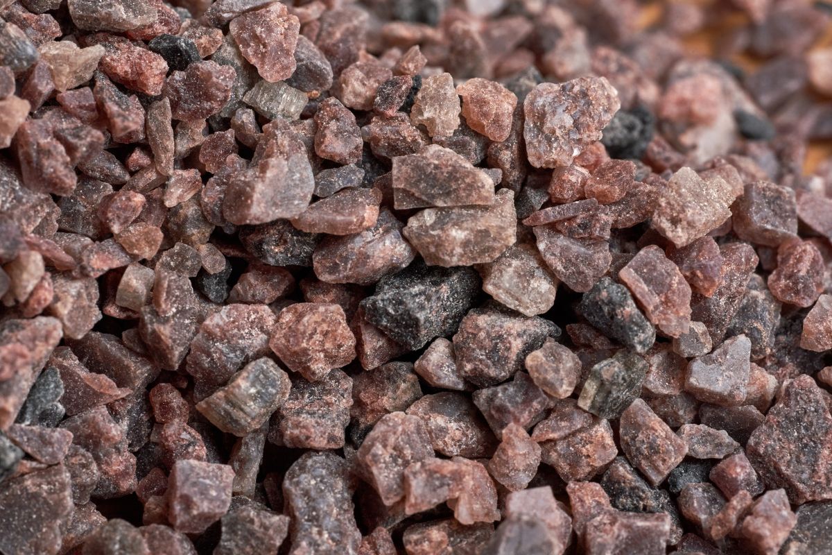 A close up of large grains of black Himalayan salt, showing the range of dark colours.