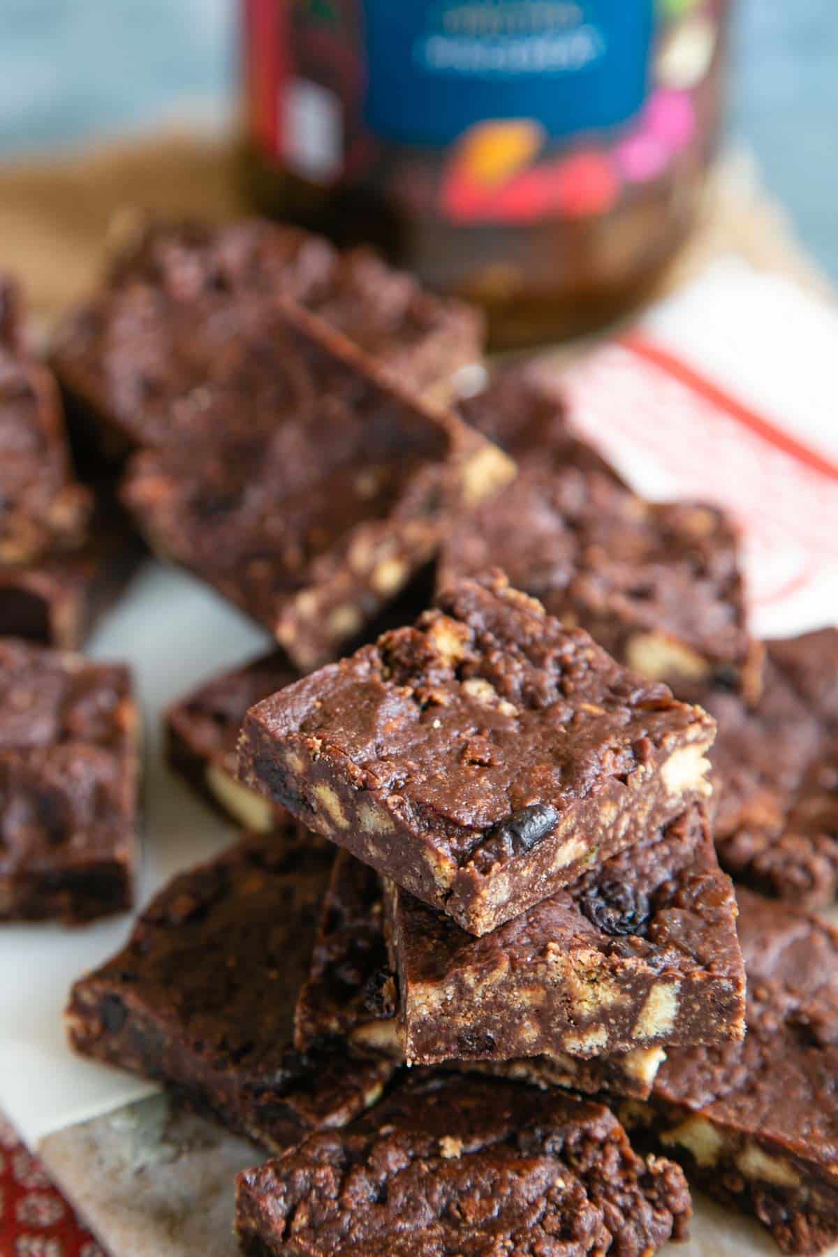 Mincemeat tiffin sqaures laid out on a platter, dark chocolatey slices flecked with biscuit and juicy fruit.
