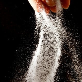 A handful of salt falls from a hand/
