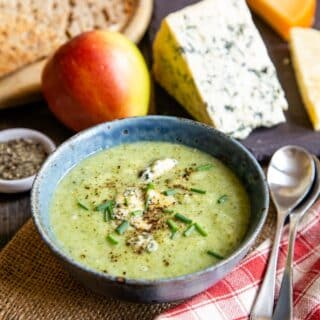 A dish of warming broccoli stilton soup with an apple and a wedge of Stilton.