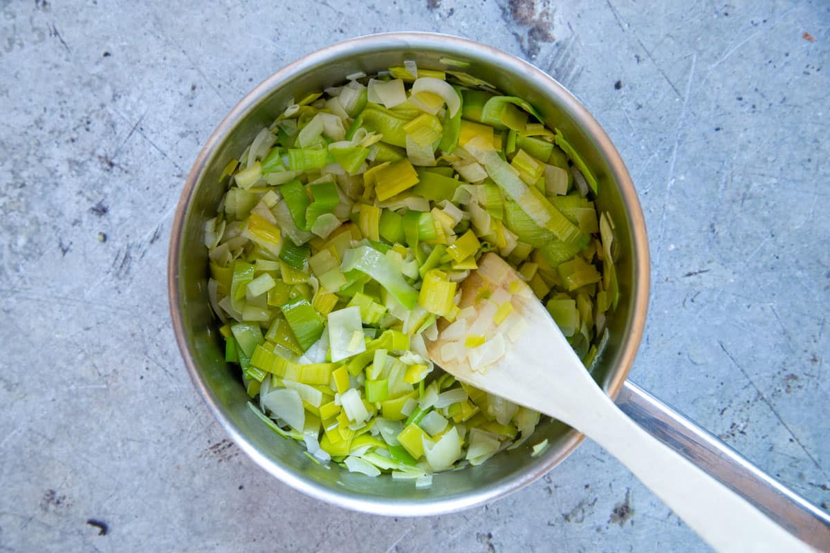 Stirring leeks and onions in the pan. They will reduce in volume as they soften.