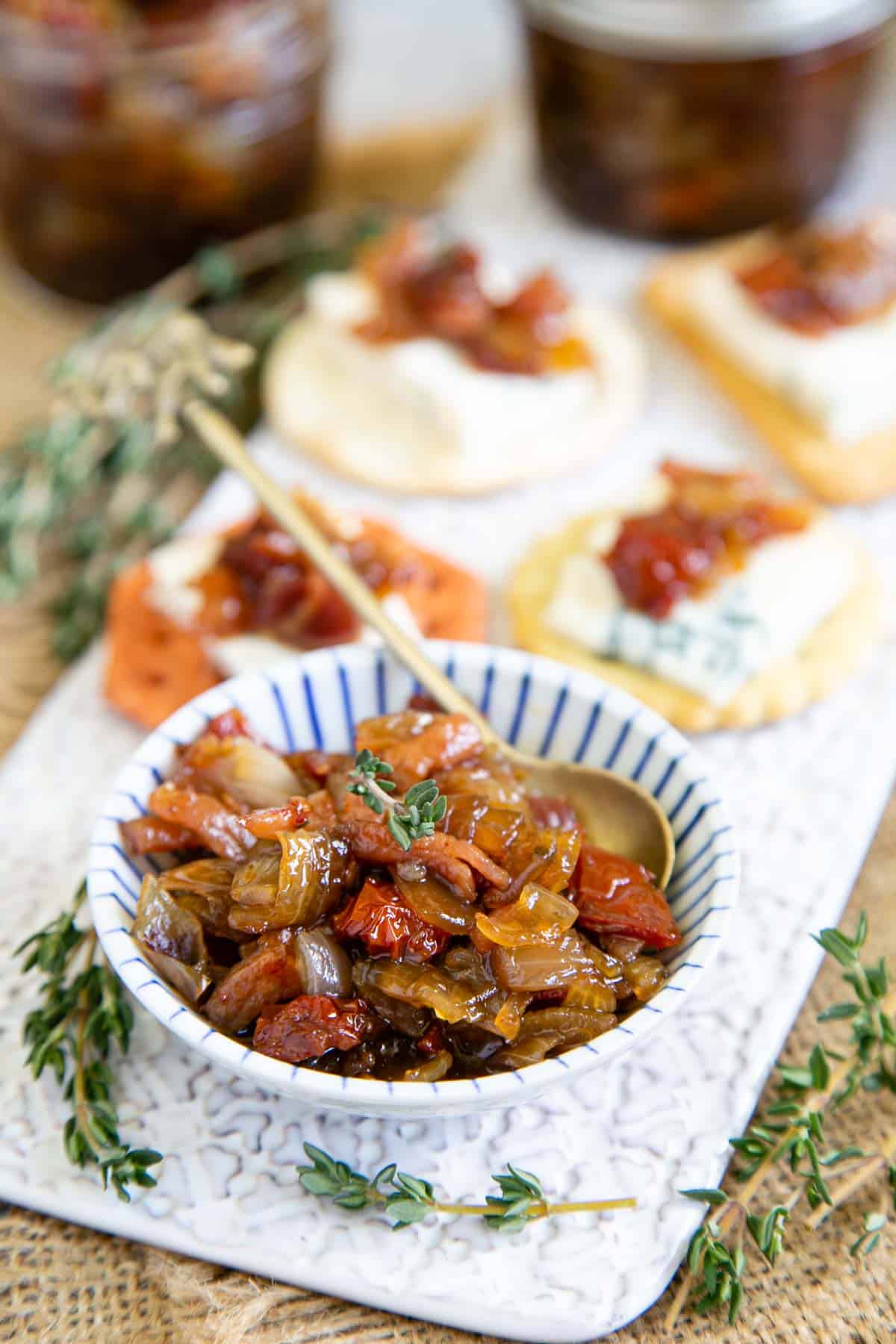 Tomato and bacon jam in a little blue and white bowl on an stylish cheeseboard with cheese and crackers - a little goes a long way!