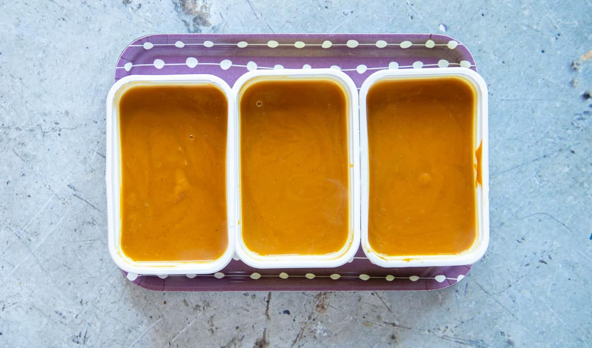 Butternut squash and sweet potato soup divided into portions in takeaway trays, ready for the freezer.