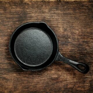 A well seasoned cast iron pan, shining on top of a wooden surface.